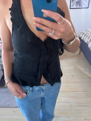 Svart omlott linnetopp med volang - Jättefin oanvänd topp från Nelly! Knytning i nacken och djup fin rygg!