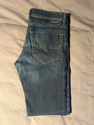 Diesel Tepphar slim jeans - Säljer ett par mörkblå slim jeans från Diesel med klassisk femficksdesign och kontrastsömmar. Jeansen har en smal passform och är tillverkade i stretchigt denimtyg för extra komfort. Perfekta för en avslappnad och stilren look. Skriv för mått!