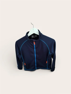 Neomondo Fleece / Träningströja (Stl 152 / 12 år) – Mörkblå - Säljer en smidig och funktionell tröja från Neomondo. Perfekt som mellanlager under jackan kalla dagar eller som en sportig tröja i skolan/på träningen.  Mörkblå bas med snygga kontrastdetaljer (blå sömmar och orangea dragkedjor). Hel dragkedja fram och fickor med dragkedja. Materialet andas bra.  Skick: Mycket fint skick! Ser sparsamt använd ut, hel och ren.  Storlek: 12 år / 152 cl. 