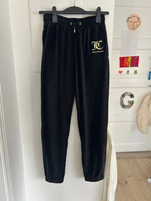 Svarta velourbyxor Juicy Couture - Säljer ett par svarta mjukisbyxor från Juicy Couture i mjuk velour. Byxorna har resår i midjan med dragsko, guldfärgade detaljer och logga broderad framtill. Perfekta för en chill och trendig look. Är i storlek 14/15, vilket är som S