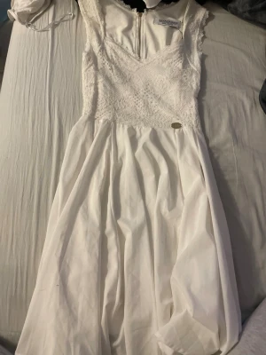 Vit spetsklänning från Chiara Forthi - Superfin vit klänning från Chiara Forthi med spets upptill och v-ringning. Klänningen är ärmlös och har en lätt utställd kjol i mjukt tyg. Perfekt för sommarens alla tillfällen och studentfirande.