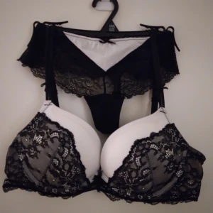 Svart och vitt spets BH set, pushup, 75A.  - Väldigt fint, feminint set om svart och vit BH med detaljerad spets och push-up effekt. Toppen har justerbara axelband och hakknäppning bak. Spetsen ger en lyxig vibe och kontrasten mellan svart och vitt gör den extra iögonfallande. Perfekt för dig som gillar att sticka ut. Strlk 75A. Trosa 36, oanvänd. BH har en liten missfärgning upptill på framsidan, går eventuellt bort vid handtvätt. I övrigt är den i nyskick. Se bilder för egen bedömning.