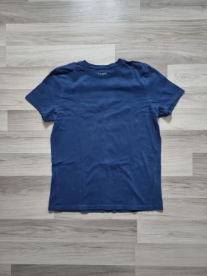 Marinblå basic t-shirt - En enkel marinblå t-shirt med rund hals och korta ärmar från T-SHIRT. Tillverkad i mjuk bomull för en bekväm känsla. Perfekt till jeans eller shorts för en avslappnad look.