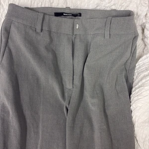 Grå kostymbyxor från Bikbok - Snygga grå kostymbyxor från Bikbok i storlek tall. Jätte sköna och fina. Uppsydda nere men lätte sömmar som man kan sprätta upp!