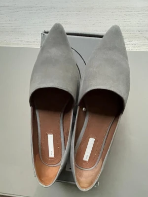 H&M Premium ballerinas 37 - Minimalistiska H&M Premium ballerinor i ljus mullvadsfärg (mole light) i storlek 37. Färgen är inte grå utan närmast en fin greige, se speciellt den första bilden. Äkta nubuck eller mocka, se märkningen på skorna. Snyggt använda. Motsvarar sin storlek.