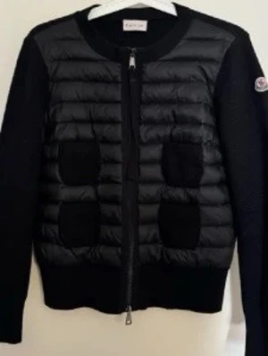 Svart cardiganjacka  - Förnyar annons Snygg svart cardiganjacka med quiltad front och stickade ärmar. Dragkedja framtill och fyra dekorativa fickor på framsidan. Perfekt för lager på lager och streetstyle. Nfc, taggar och scann finns! Priset kan diskuteras vid snabb affär! 