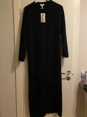 Svart långklänning från Object - ny med prislapp  - Stickad klänning - från Object - ny med prislapp Superfin stickad klänning! Kraftig tyg!  Slits bak!  Klänningens totala längd 135 cm   Hals: Rundad Passform: Regular Fit Snitt: Rak Längd: Lång    Material: 52% viskos, 28% polyester, 20% nylon Tyg: Stickat Skötselråd: 30 °  