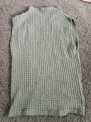 Grön ribbad ärmlös topp - Säljer en ljusgrön ärmlös topp med ribbad struktur. Toppen har hög hals och är tillverkad i ett mjukt, stretchigt material som ger en skön passform. Perfekt att styla med jeans eller kjol för en trendig look.