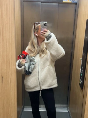 Krämvit teddyjacka med dragkedja - Supermjuk teddyjacka i krämvit färg med hög krage och två stora fickor framtill. Jackan har en rak, avslappnad passform och stängs med dragkedja. Lite smink i kragen men går att tvätta bort 🩷