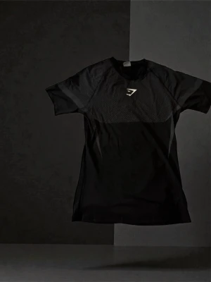 Svart träningströja från Gymshark - Snygg svart träningströja från Gymshark med meshpaneler över bröst och rygg för extra ventilation. T-shirten har korta ärmar, rund hals och en diskret logga på bröstet. Perfekt för gymmet eller löprundan.