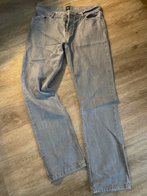 Grå raka jeans från Monte’n - Säljer ett par grå jeans från Monte’n med rak passform och klassisk femficksdesign. Jeansen har normal midja och är tillverkade i ett mjukt denimtyg. Perfekta för dig som gillar en enkel och clean stil.