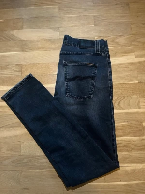  Nudie Jeans - Snygga mörkblå jeans från Nudie Jeans med klassisk femficksmodell och diskret logga på bakfickan. Jeansen har normal passform och är tillverkade i mjuk bomull med en lätt tvättad look. Perfekta för en avslappnad stil. Lean Dean model. Skriv för fler frågor 