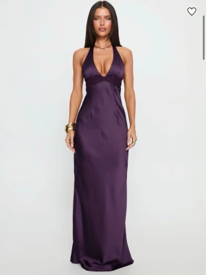 Lila långklänning med öppen rygg - Elegant lila långklänning i satinliknande material med en v-ringning och halterneck. Klänningen har öppen rygg med knyt i nacken och en figurnära passform. Den var något för liten för mig, därav säljer jag den, men den är helt ny med prislappen kvar! Köptes för 1350kr (frakt från UK tillkommer därav blev den dyrare än vad det står på hemsidan) 
