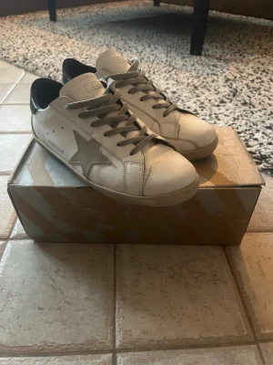 Golden Goose skor  - Golden Goose sneakers ,Kommer med originalkartong och dustbag. Storlek 42 med mörkblå detaljer på hälen. Kommer med box,dustbag och taggar