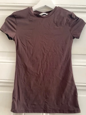 Brun kortärmad t-shirt - Snygg basic brun t-shirt i superskönt material! Oanvänt/nyskick (endast tvättad och provad en gång). Storlek: XS.