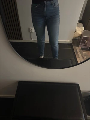 Blå slim fit jeans med hög midja - Snygga blå slim fit jeans med hög midja och klassisk femficksdesign. Jeansen har en lätt tvättad look och raka ben. Perfekta för en avslappnad och trendig stil. Materialet är denim i bomull.