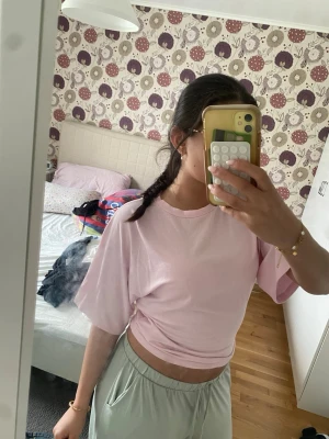 Ljusrosa croppad t-shirt - En ljusrosa croppad t-shirt med korta ärmar och rund halsringning. T-shirten har en loose passform och är tillverkad i mjuk bomull, perfekt för en avslappnad och trendig look.