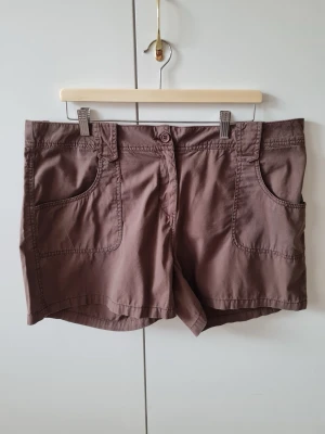 Shorts från N.Y. Near You strl XL (dam) - Snygga bruna shorts från N.Y. Near You med stora framfickor och bakfickor med lock och knapp. Klassisk passform med bälteshällor och knappstängning framtill. Perfekta för varma dagar! Storlek XL. Kan hämtas i Vallentuna.