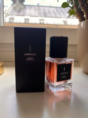 YSL Jumpsuit Vibrant Magnolia parfym - Exklusiv parfym från Yves Saint Laurent, Jumpsuit Vibrant Magnolia. Doften har en fräsch och blommig karaktär med magnolia som huvudnot. Snygg och stilren design som passar perfekt på parfymhyllan. 100% kvar 