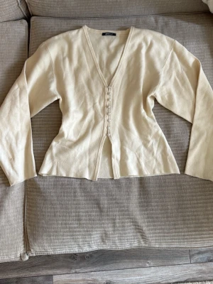 Ljusbeige kofta med knappar - Beige kofta med v-ringning från Gina Tricot. Använd ett par gånger men i bra skick. 💓 Liten fläck på högra ärmen.
