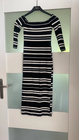 ZARA Svartvit randig långklänning - Snygg långklänning med svarta och vita horisontella ränder. Klänningen har trekvartsärm och en offshoulder-ringning som ger en trendig look. Perfekt för dig som gillar stilrena mönster och enkel design.