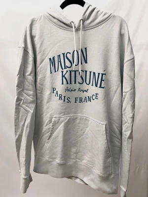 Maison Kitsuné Hoodie - Hoodie från Maison Kitsuné i en snygg ljusblå/grå färg! Nyskick, inga defekter. Står XL men sitter mer som M/L. Modellen är ca 182. Kontakta mig för fler frågor och funderingar!