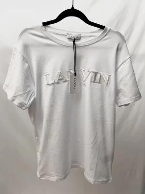 Vit Lanvin Tshirt - Väldigt stilren och unik Tshirt från det exklusiva märket Lanvin! Helt ny med tags. Storlek S, sitter normalt. Kontakta mig för fler frågor och funderingar!