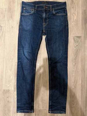 Nudie Jeans Lean Dean Dry 16 Dips Jeans Mörkblå W32/L32 - Slim Tapered Fit - Nudie Lean Dean Dry 16 Dips mörkblå jeans i dry denim med slim tapered fit passform som sitter smalt men bekvämt och funkar till allt, storlek W32/L32, midja 41 cm, ytterbenslängd 101 cm, benöppning 15 cm, modellen är 185cm & väger 65kg, i fint skick.