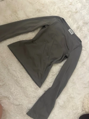 Grå långärmad topp från Weekday - Snygg grå långärmad topp från Weekday med figurnära passform och rund halsringning. Tillverkad i ett stretchigt och mjukt material som sitter skönt på kroppen. Perfekt att styla med jeans eller kjol för en clean look.