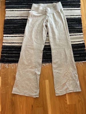 Grå mjukisbyxor från Gina Tricot - Superbekväma grå mjukisbyxor från Gina Tricot med bred ribbad midja och dragsko. Byxorna har raka ben och är gjorda i mjukt material som passar perfekt för en avslappnad stil. Enkla att matcha med hoodies eller t-shirts.