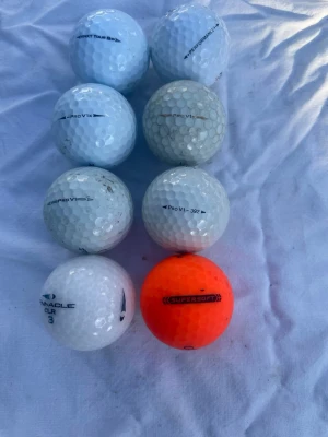 8 fina golfbollar mixade märken och färger - Säljer ett gäng golfbollar från olika märken som Titleist Pro V1, Pinnacle och Callaway Supersoft. Bollarna är mestadels vita men en är orange. Perfekt för dig som vill fylla på golfbagen med blandade bollar.