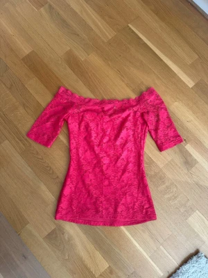 Rosa offshoulder spetsblus Gina Tricot - Säljer en snygg rosa offshoulder spetsblus från Gina Tricot. Toppen har trekvartsärm och är gjord i ett stretchigt spetsmaterial med fina detaljer längs kanten. Perfekt för dig som vill sticka ut lite extra med en feminin och trendig look.