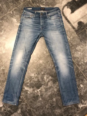 Blå slim fit jeans från Jack & Jones - Ljusblå jeans från Hollister med slim fit passform och klassiska fem fickor. Jeansen har snygga slitningar på låren, normal midja och stängs med dragkedja och knapp. Tillverkade i mjuk denim med lite stretch för extra komfort.