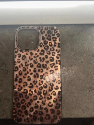 Mobilskal med leopardmönster - Snyggt mobilskal med glansigt leopardmönster i brons och svart. Skalets form är anpassad för en mobil med större kameralins. Tillverkat i plastmaterial som ger ett coolt och trendigt intryck. Perfekt för dig som vill sticka ut med din mobil.