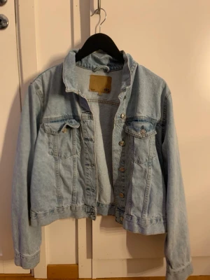 Ljusblå jeansjacka från 157 - Ljusblå jeansjacka från 157 med klassisk krage, två bröstfickor med lock och knapp samt knappstängning framtill. Jackan har en avslappnad passform och är tillverkad i denim. Perfekt för en cool och enkel stil. Den passar även mig som har vanligtvis S