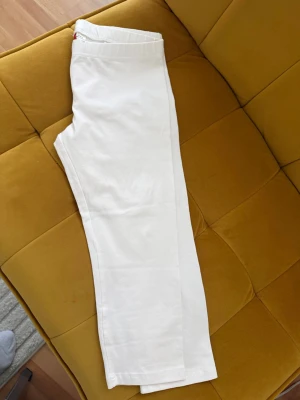 Vita leggings med resårmidja - Säljer ett par vita leggings med rak passform och bekväm resår i midjan. De är tillverkade i ett mjukt och stretchigt material som sitter skönt på kroppen. Perfekta att styla med oversized tröjor eller hoodies.