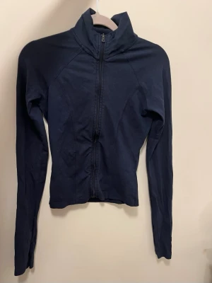 Mörkblå sportjacka med dragkedja - Långärmad modell i stretchigt material, perfekt för träning eller löpning. Snygg och enkel design utan synliga loggor eller mönster. Som man ser på bild tre är dragkedjan lite missfärgad men det syns inte när man har på sig den, eller jag tycker inte att det är något som man tänker på💕