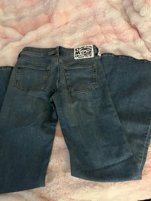 Vida blå jeans från Cheap Monday - Säljer ett par blå jeans från Cheap Monday flared med klassisk femficksdesign. Jeansen har en cool patch med logga bak i midjan och är gjorda i denim. Perfekta för dig som gillar retrostil och vill sticka ut. Helt oanvänd blev för små i midjan