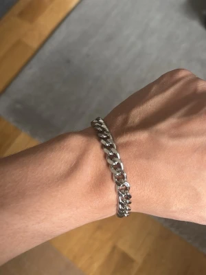 Silver armband - Snyggt kedjearmband i silverfärgad metall med breda länkar och en platt bricka som detalj. Armbandet har en klassisk och stilren design som passar till många olika looks. Perfekt för dig som gillar minimalistiska accessoarer. Det är rostfristål inte äkta silver