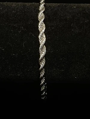 Snyggt tvinnat silverfärgat armband - Ett stilrent armband i silverfärg med tvinnad design. Armbandet har en klassisk och tidlös look som passar perfekt till olika stilar. Tillverkat i metall med en snygg glansig finish. Perfekt accessoar för att lyfta din outfit.