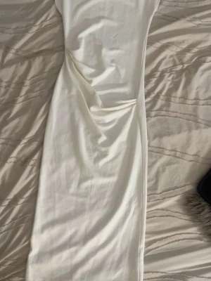 Vit långklänning i mjukt tyg - Säljer en elegant vit långklänning med enkel och stilren design. Klänningen har en rak passform och är ärmlös, vilket ger en modern look. Perfekt för dig som gillar minimalistisk stil och vill ha något klassiskt i garderoben.Vit elegant klänning säljes 🤍  Har endast använt denna klänning en gång på skolavslutningen. Den är i mycket fint skick, nästan som ny. Inga fläckar eller skador och den är nytvättad.  Perfekt för student, skolavslutning, fest, födelsedag eller andra speciella tillfällen. Kl