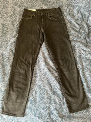 Svarta raka jeans - Snygga svarta jeans med klassisk femficksdesign och raka ben. Jeansen har normal midja och stängs med dragkedja och knapp. Perfekta till en avslappnad streetstil eller att matcha med en hoodie.