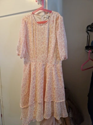 Blommig volangklänning  - Ny oanvänd söt klänning från bubbleroom med blommigt mönster i rosa. Klänningen har volangdetaljer, rund halsringning och trekvartsärm. Perfekt för vår och sommar med sitt luftiga material och romantiska look.