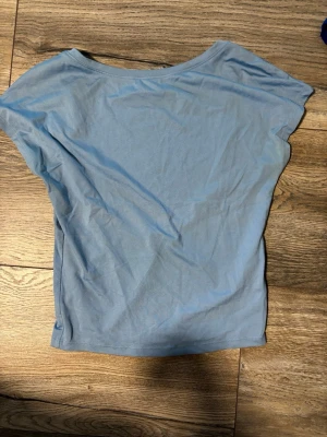 Ljusblå topp med öppen rygg - Snygg ljusblå topp med korta ärmar och en öppen rygg. Tillverkad i mjuk bomull, perfekt för en trendig och avslappnad stil. Enkel design som passar till många outfits.