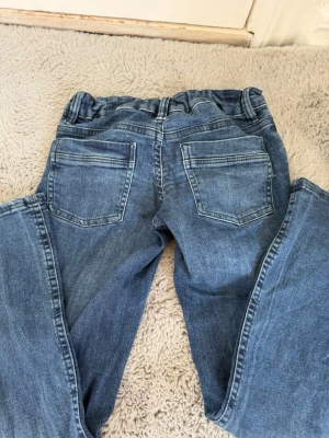 Lågmidjade utsvängda blåa jeans - Ett par blåa jeans från Gina tricot i storlek 158. De är utsvängda och lådmidjade.