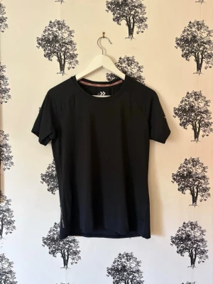 Svart tränings-tshirt från Lager 157 - Säljer en svart tränings-tshirt från Lager 157 med rund hals och korta ärmar. Materialet är lätt och snabbtorkande, perfekt för gym eller löpning. Diskret logga på insidan av halsen. Snygg och enkel design som passar till all sport.