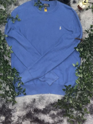 Ralph Lauren tjock tröja. Storlek M (Youth xl). - Snygg blå stickad tröja från Polo Ralph Lauren med rund halsringning och diskret broderad logga på bröstet. Tröjan har långa ärmar och ribbade muddar vid ärmslut och nederkant. Perfekt för en stilren och avslappnad look. storlek M i storlek och storlek xl i ungdoms storlek.