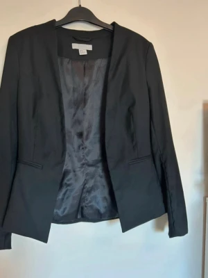 Kavaj - Svart kavaj från H&M i mycket fint skick. Fejk-fickor framtill. Går inte att stänga igen kavajen. Material: Polyester, Viskos, Elastan