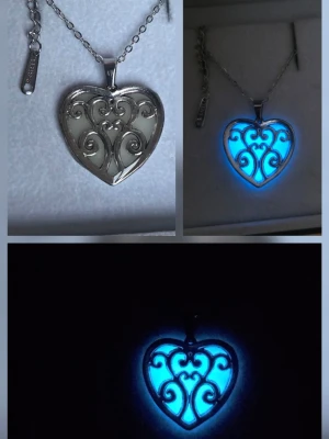 Självlysande hjärthalsband - blått sken i mörkret - Handgjort självlysande halsband. I dagsljus ser halsbandet ut som ett elegant hjärtsmycke. När omgivningen blir mörkare börjar hänget avge ett tydligt blått sken.  Vanligt dagsljus räcker för att aktivera effekten och smycket börjar lysa i dämpat ljus och mörker.  Ljuseffekten kan hålla upp till ca 12 timmar, avtar gradvis över tid och är tydligast i början av mörkret. Detta är normalt för självlysande pigment. Både hänget & kedjan tål vatten, missfärgas ej. Hängets storlek: ca 2,4 cm. 