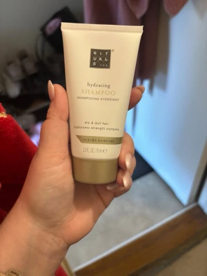 Rituals hydrating shampoo 70 ml - Lyxig hydrerande shampoo från Rituals för torrt och livlöst hår. Innehåller hyaluronic strength complex och kommer i en beige och guld tub på 70 ml. Perfekt för dig som vill ge håret extra fukt och glans.
